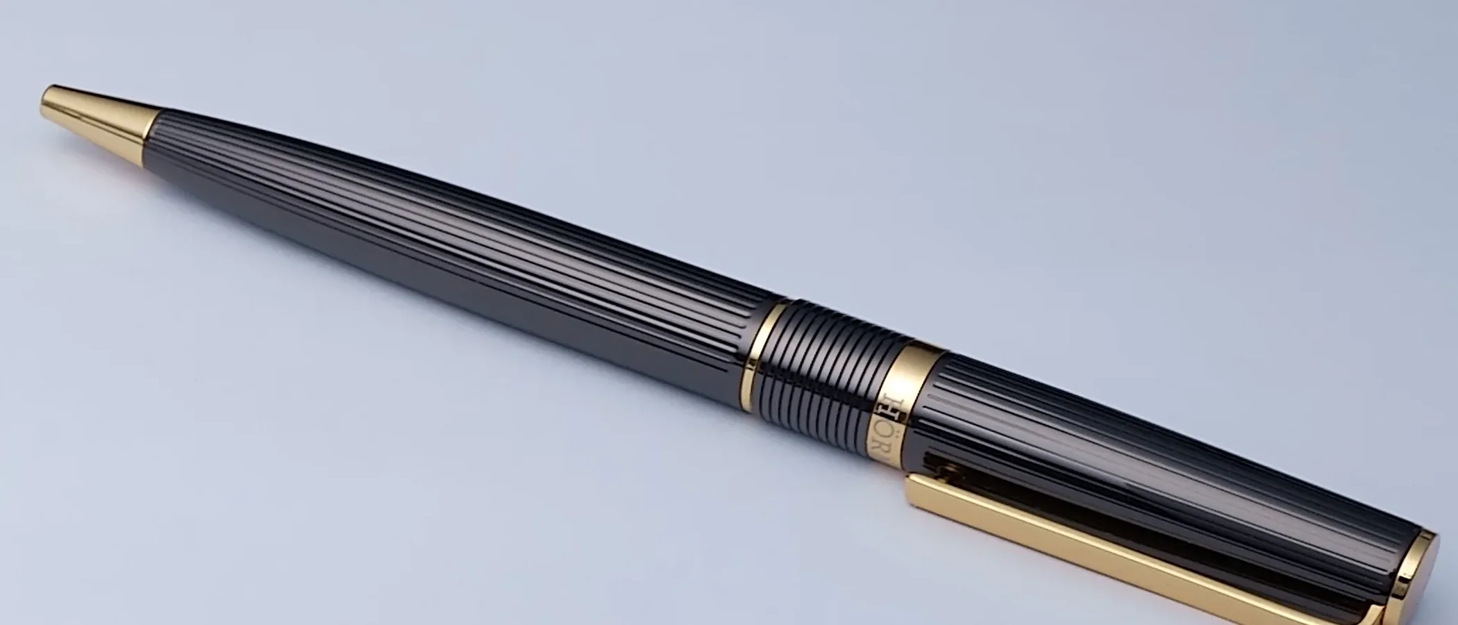 A black and gold Hörner Vectrum ballpoint pen on a pale surface