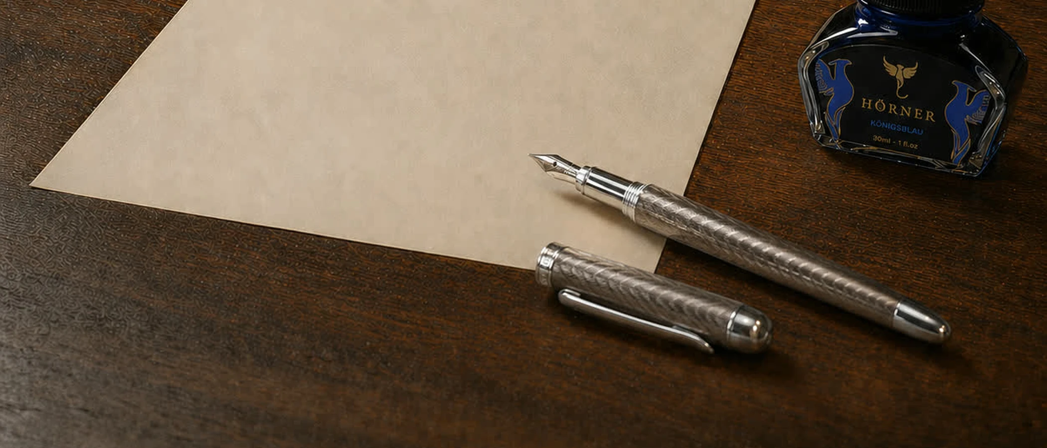 A sheet of blank cream paper with a fountain pen and a bottle of ink