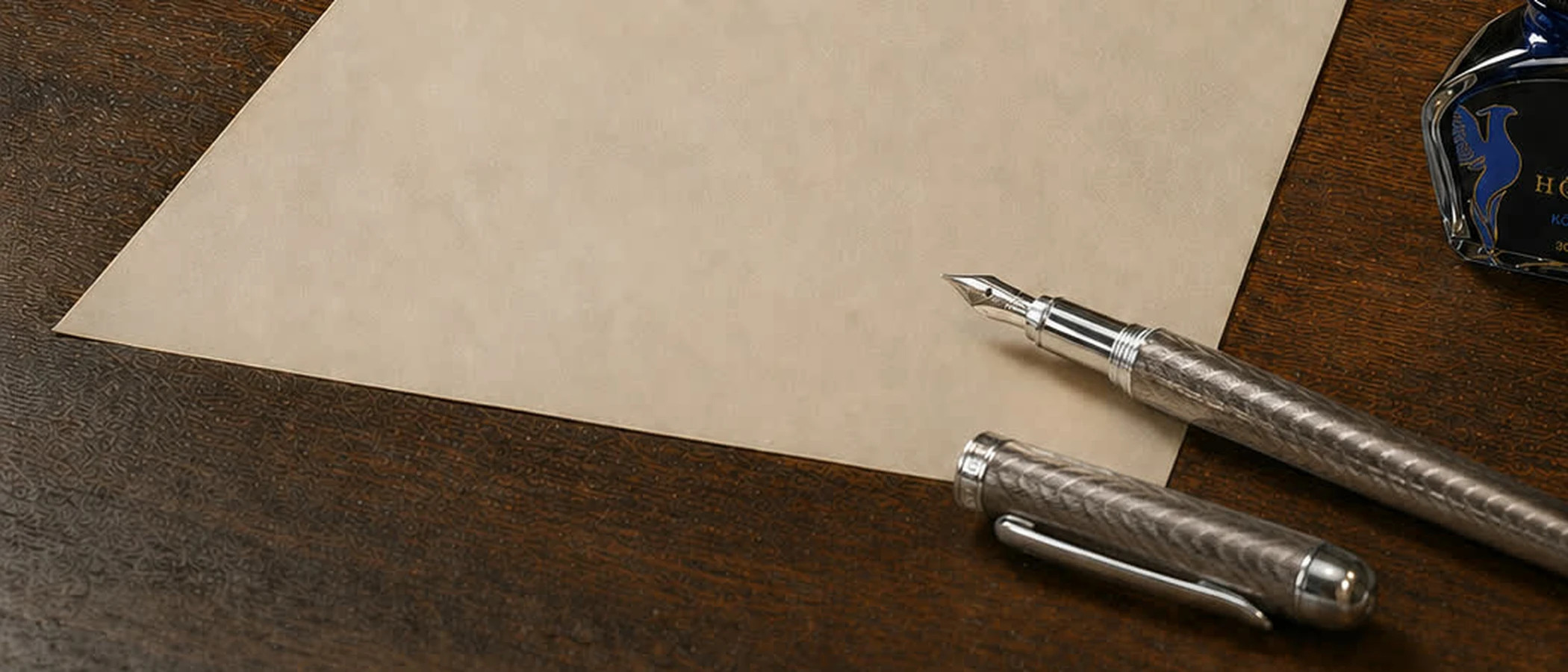 An uncapped fountain pen resting at the edge of a blank sheet of cream paper