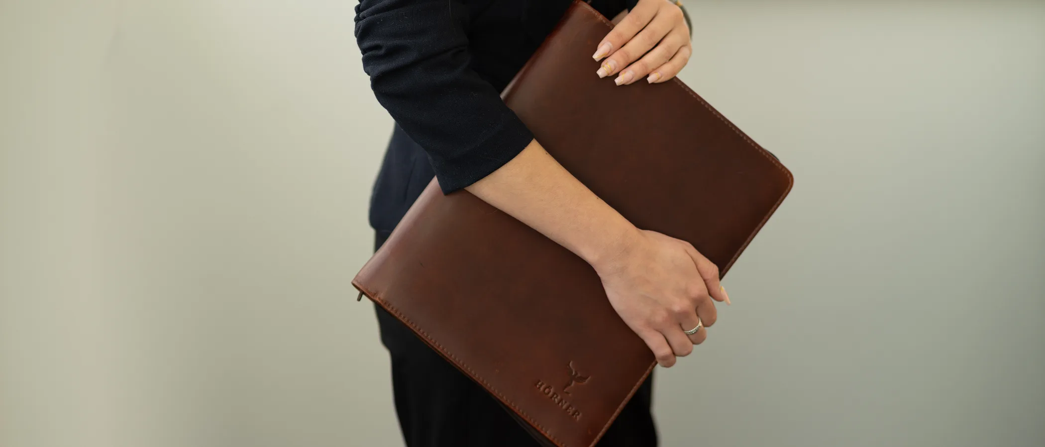 A professional in a dark suit holding a Hörner cognac leather padfolio