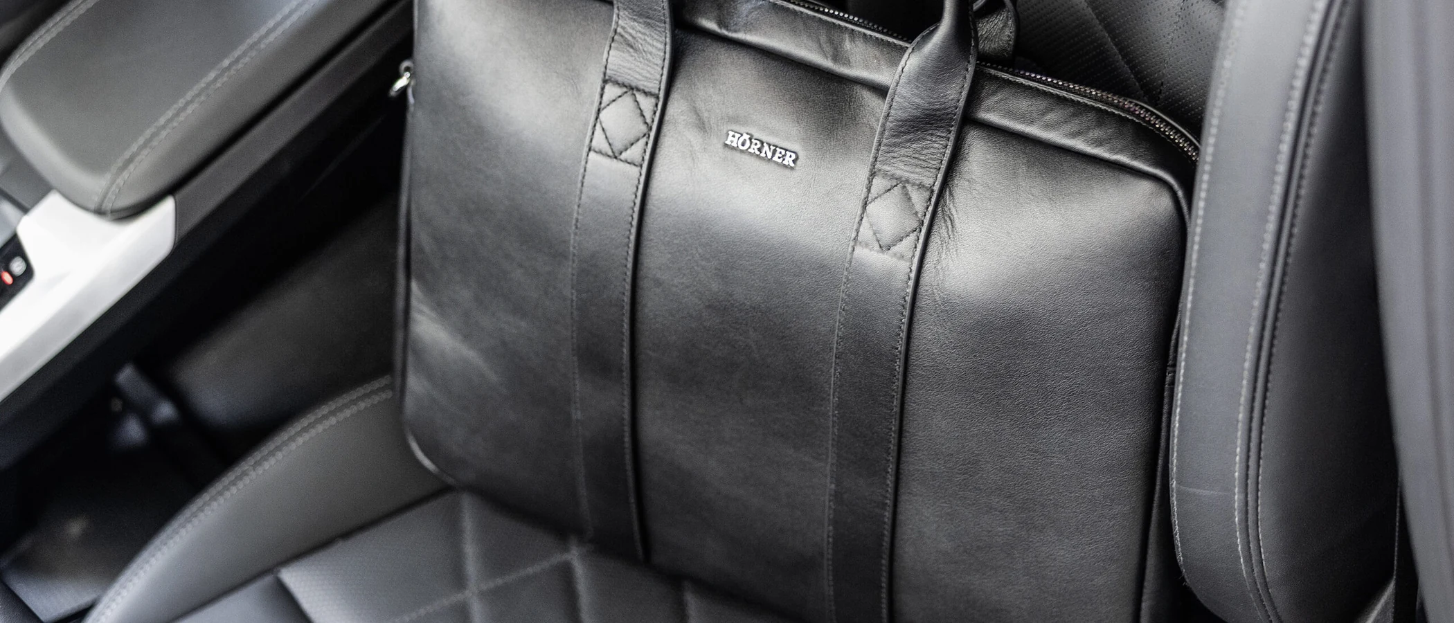 A black leather Hörner business bag resting on the seat of a car