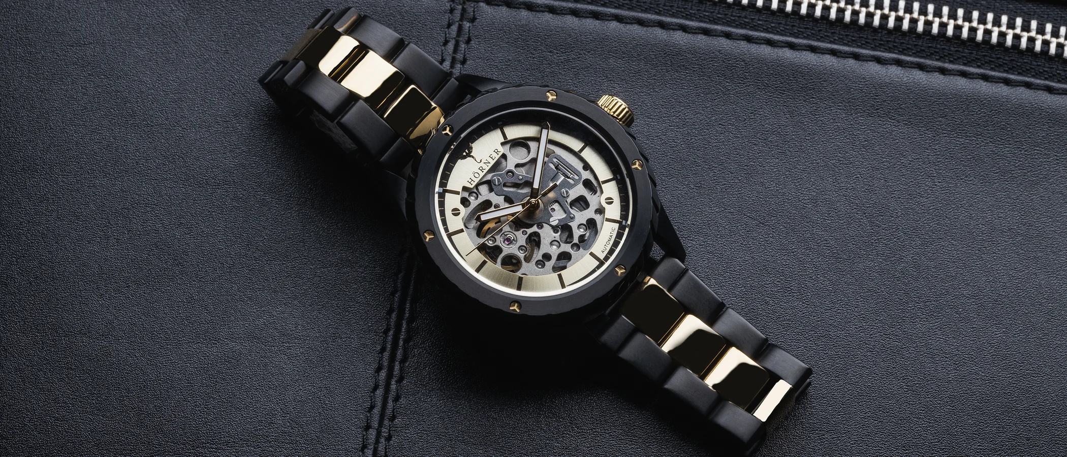 A black and gold Hörner skeleton automatic watch resting on dark leather