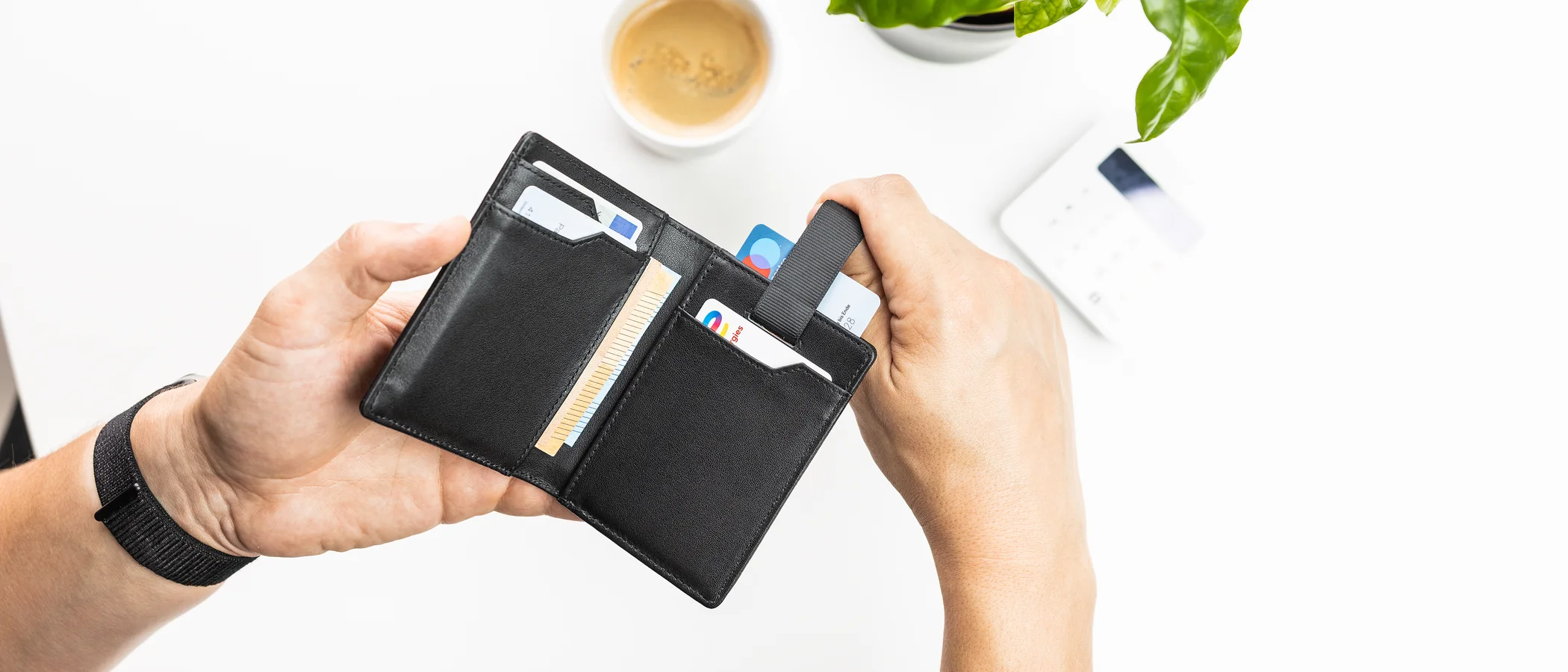An open brown leather wallet holding a few cards and a little cash