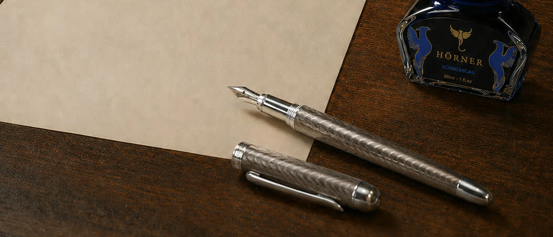 A fountain pen and its cap on a sheet of cream paper beside a bottle of Hörner ink