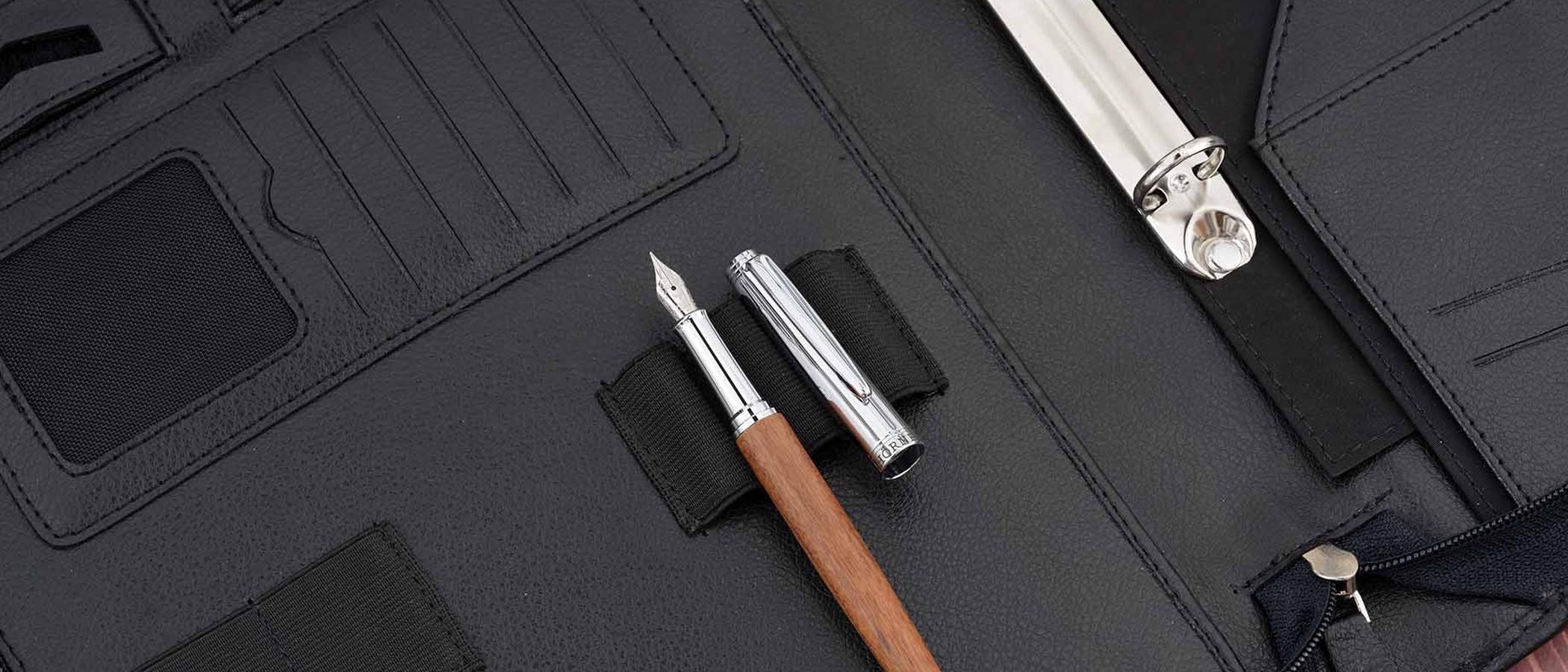 A mahogany fountain pen resting uncapped in a black leather writing folio
