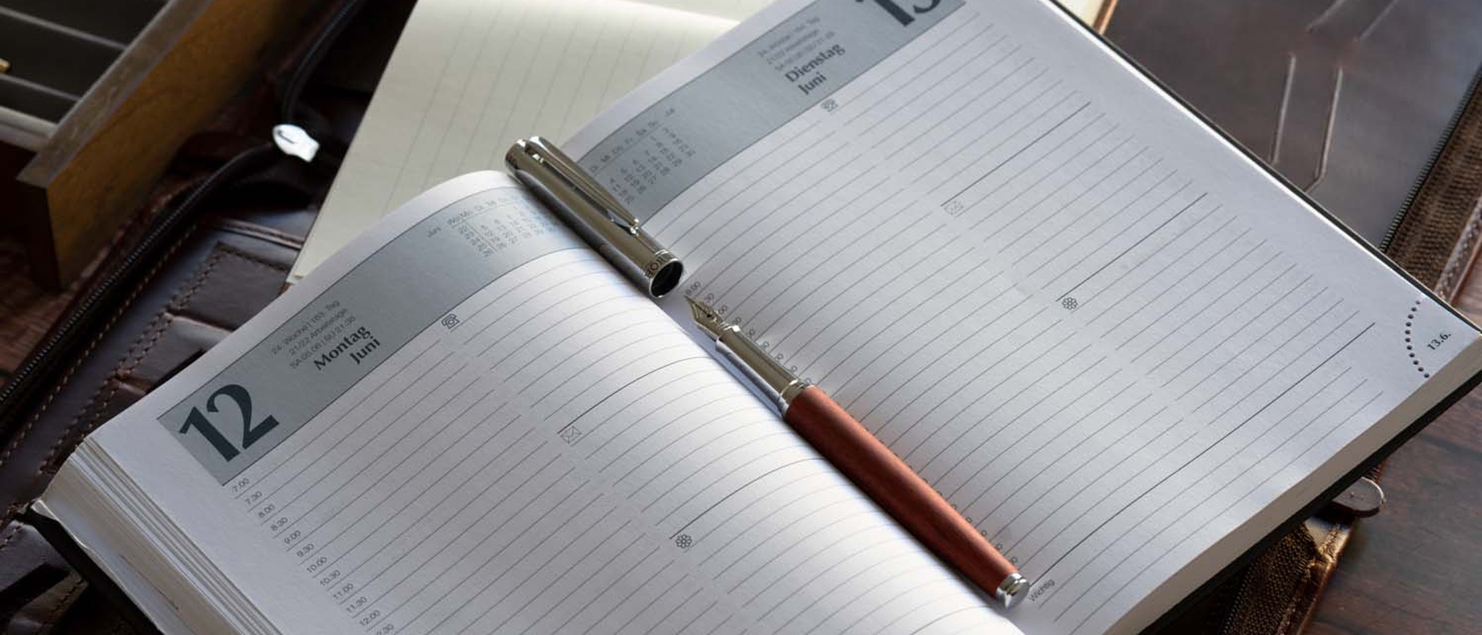 A reddish sandalwood fountain pen resting uncapped on an open planner